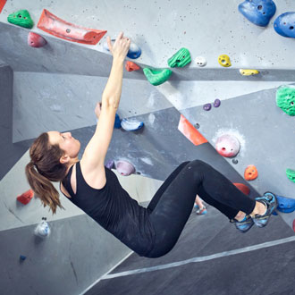 Woman on rock climbing wall at The Climbing Hangar Woman on rock climbing wall at The Climbing Hangar